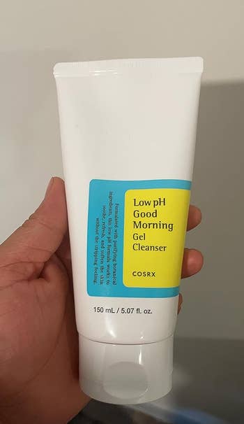 A reviewer holding the cleanser