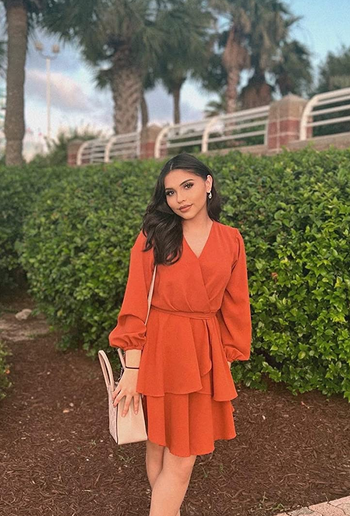 reviewer wearing the orange dress with heels