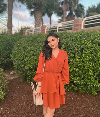 reviewer wearing the orange dress with heels