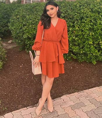 reviewer wearing the orange dress with heels