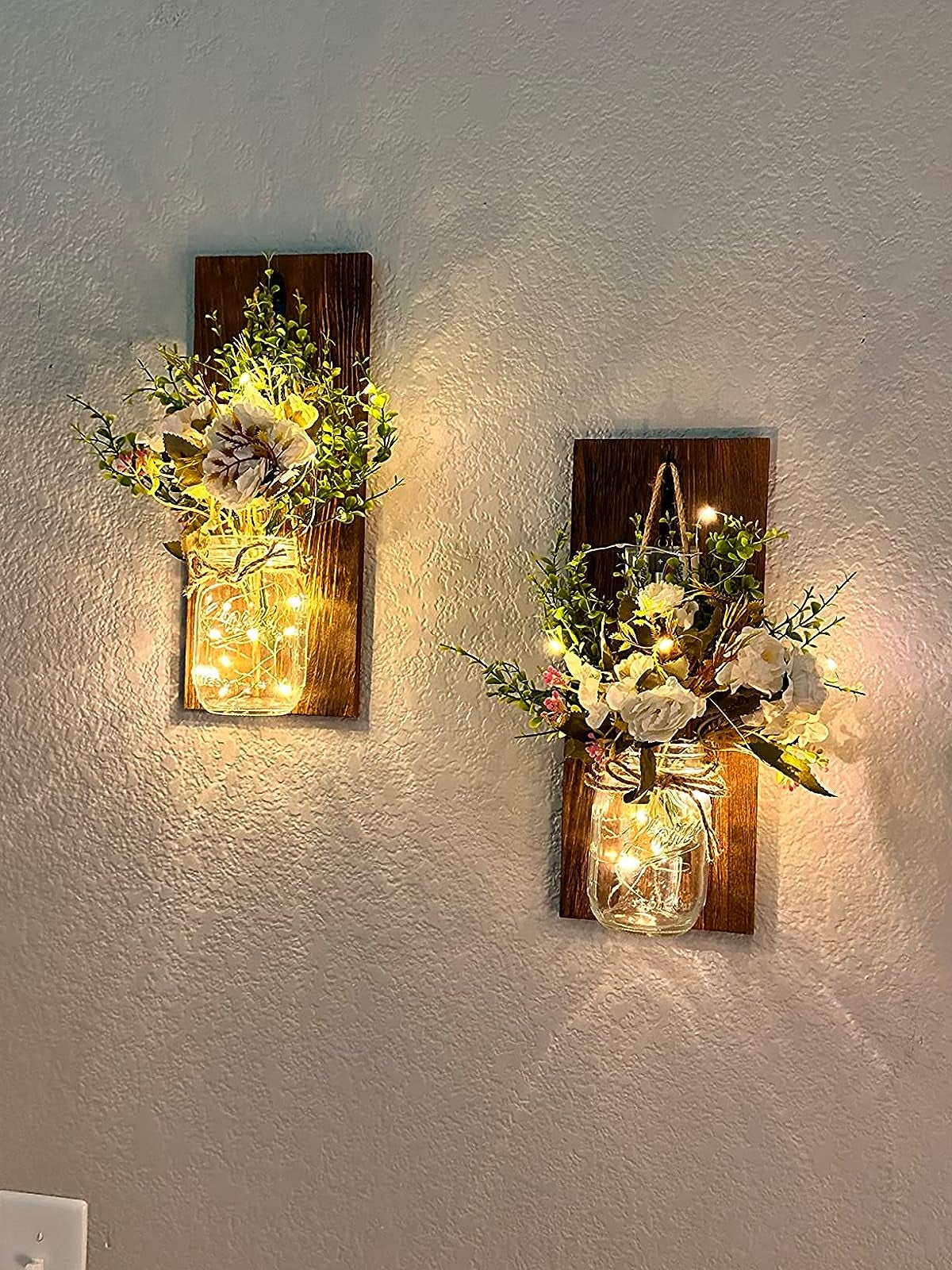two mason jars with faux flowers in it and twinkle lights