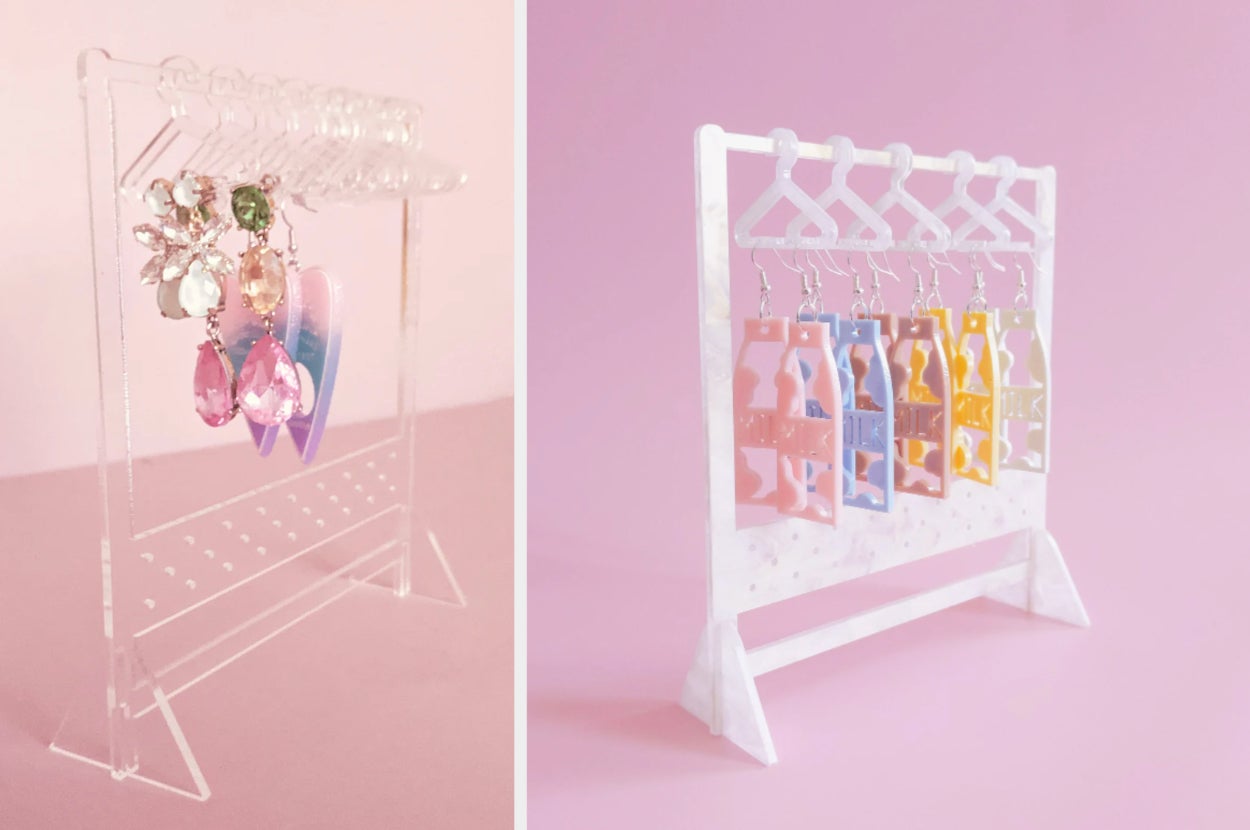 Clear plastic rack earring organizer with earrings on hangers, product in white on a pink background with earrings hanging from it