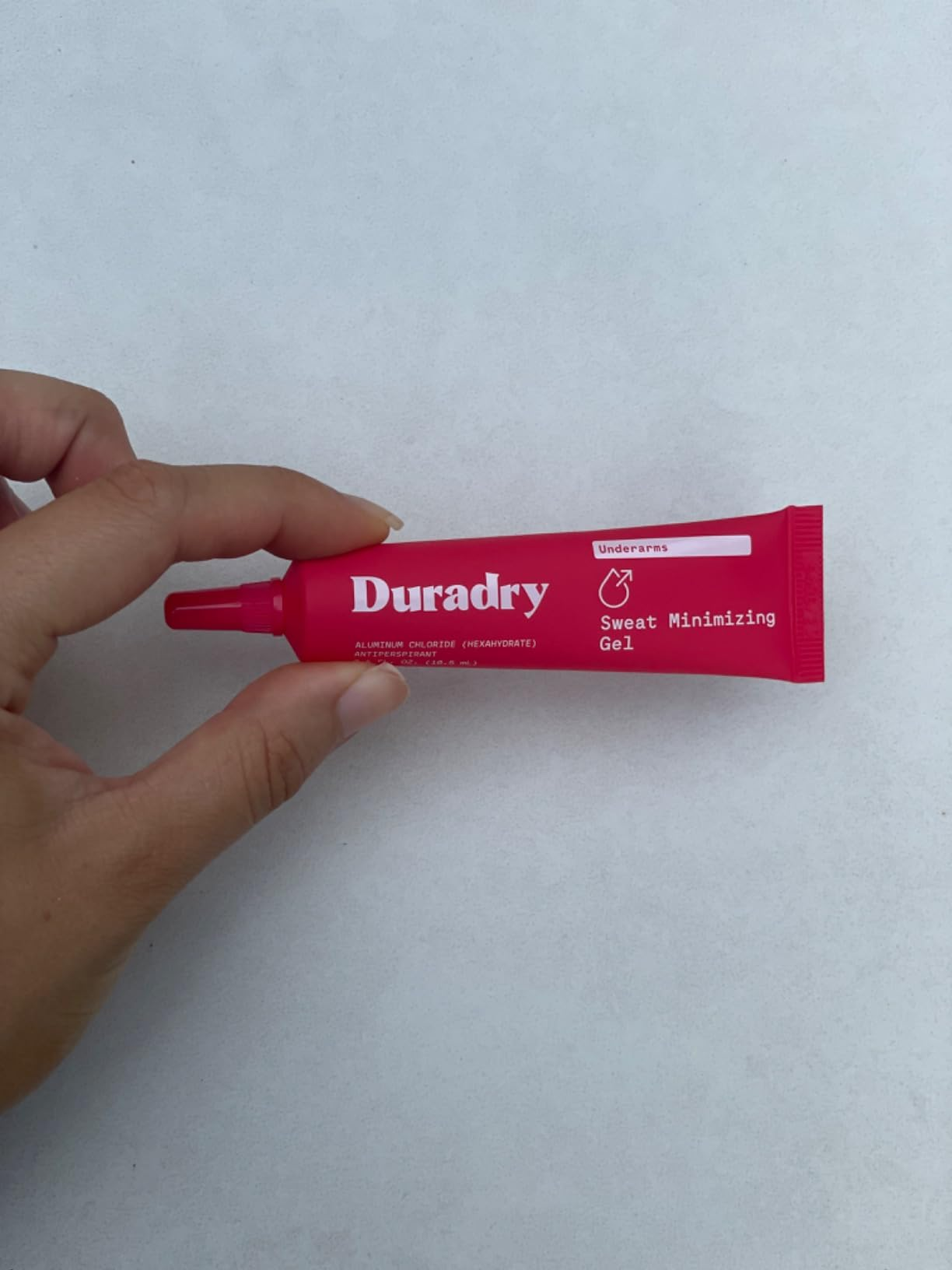 Hand holds a conduit  of Duradry Sweat Minimizing Gel, designed for underarms, highlighting its usage and packaging for a buying  context
