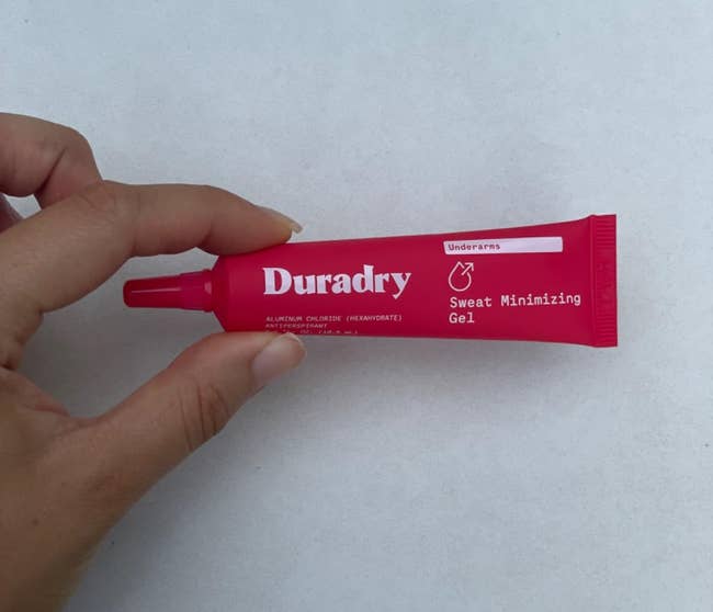 Hand holds a conduit of Duradry Sweat Minimizing Gel, designed for underarms, highlighting its usage and packaging for a buying context
