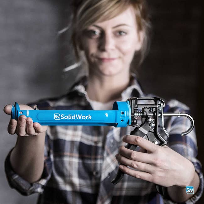 a model holding the blue caulking gun