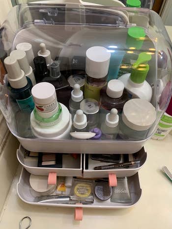 a reviewer photo of the organizer loaded with cosmetics and the bottom four drawers open 