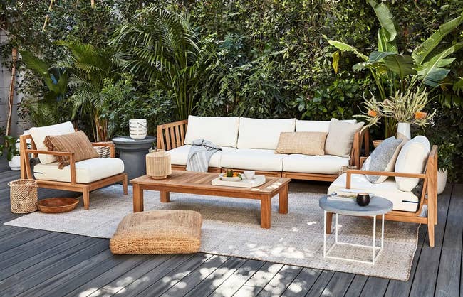 full set of matching outdoor furniture with the cream cushioned teakwood sofa in the center 