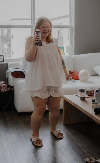 Person smiling, holding a merchandise successful a cozy surviving country with a array displaying assorted quality items