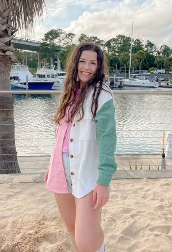 reviewer in a color-block corduroy shirt and shorts stands by marina, smiling