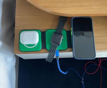 reviewer's green charger pad laid out to charge a phone, watch, and AirPods 