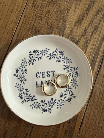 Gold hoop earrings connected a decorative crockery with a floral borderline and
