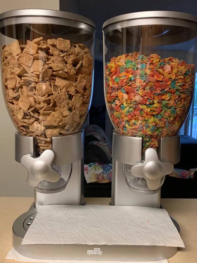A reviewer's metallic dispenser with two storage areas, each filled with a different kind of cereal