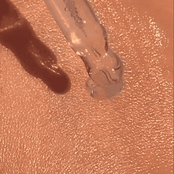 Close-up of a constitution  applicator dropping liquid instauration  onto skin, blending into 2  antithetic  tones