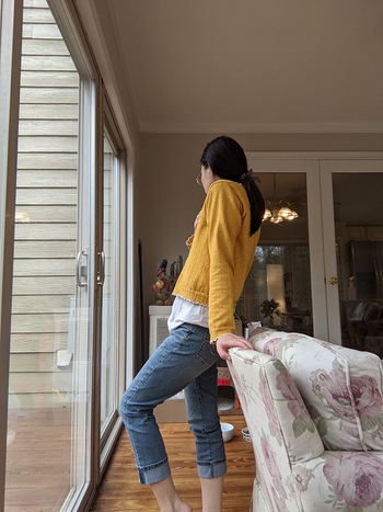 side view of reviewer wearing the cropped jeans with a yellow long sleeve top