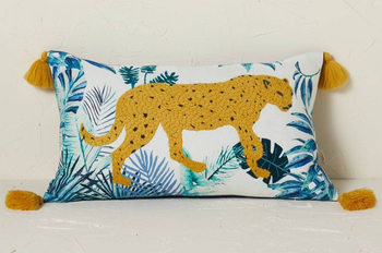 a white pillow with a blue palm print and an embroidered leopard