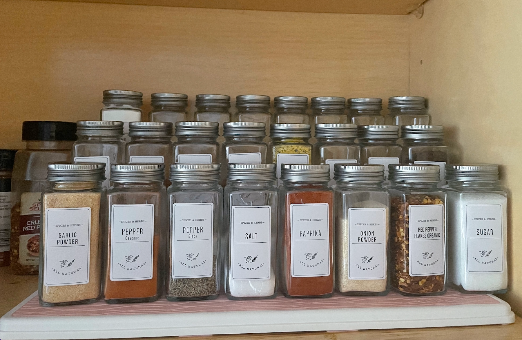 a buzzfeeder's pink and white pantry organizer holding various spice bottles