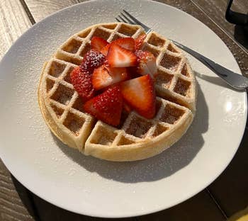 reviewer's waffle topped with powdered sugar and berries