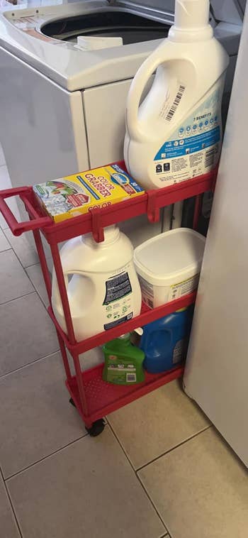 Rolling cart in laundry room holding detergent, baking soda, and cleaning supplies next to a washing machine