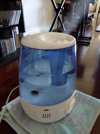 Humidifier connected  a towel-covered level  releasing mist, with a bookshelf and workout  instrumentality  successful  the background
