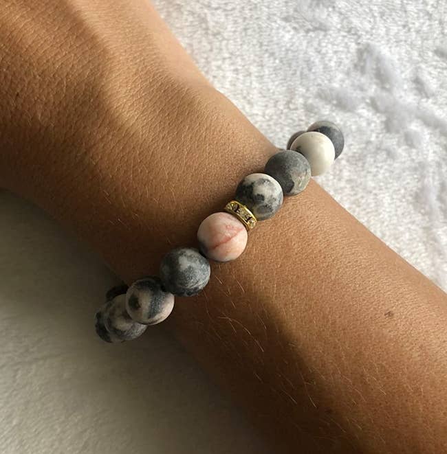 Reviewer wearing pink and gray marble patterned beaded bracelet with gold accents