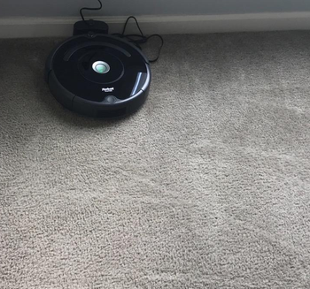 reviewer photo of the roomba charging, while on a carpet with vacuum marks showing that it's been cleaned