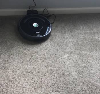 reviewer photo of the roomba charging, while on a carpet with vacuum marks showing that it's been cleaned