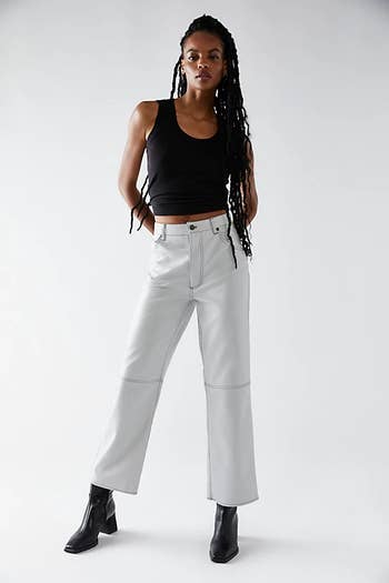 front of a model wearing stone-colored vegan leather pants with a black tank top