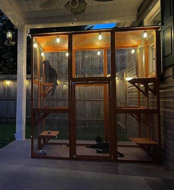reviewer's orange catio placed on a porch and covered in twinkle lights