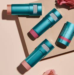 the bronze and pink balms in their blue tubes on a beige background with flowers