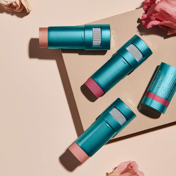 the bronze and pink balms in their blue tubes on a beige background with flowers