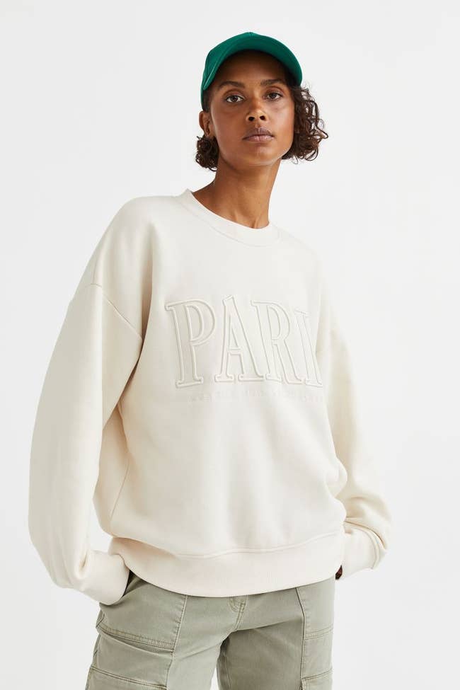 Model wearing the white sweatshirt with the word 