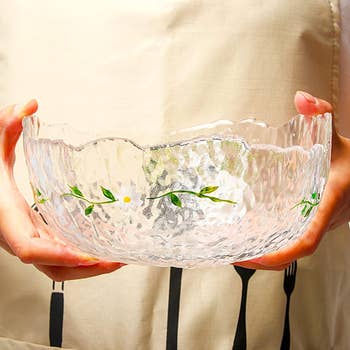 Person holding a textured solid  vessel  with embossed floral design, suitable for decorative dining