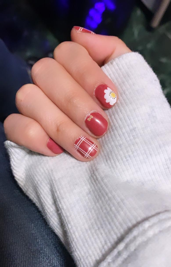 nails with the wraps applied in red designs with plaid, a little bow, and a flower
