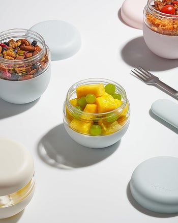 four of the containers filled with food next to a fork