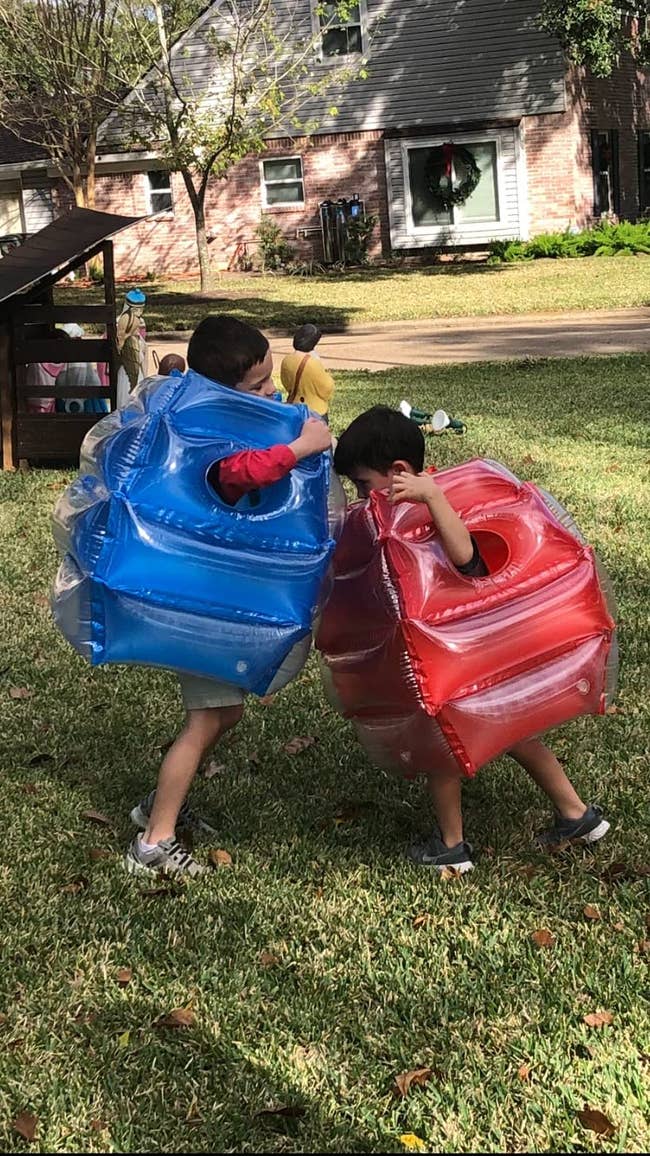 two kids wearing inflatable bubble suits and bumping into each other in them