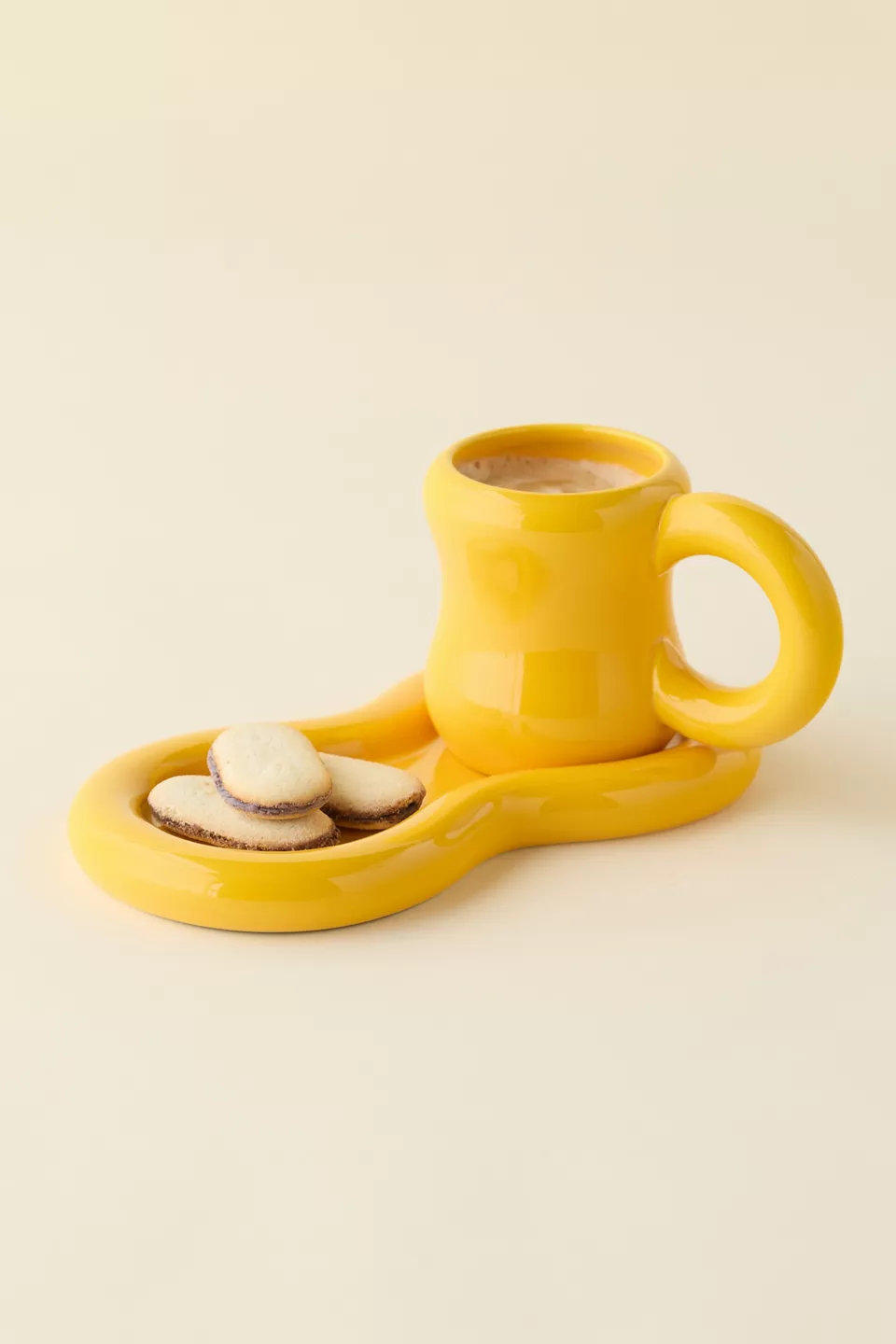 Unique ceramic mug with a wavy attached saucer holding 3  tiny  cookies, perfect  for stylish drinkware shopping