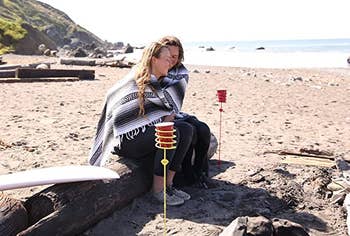a yellow stake holding a red plastic cup, placed in the sand 