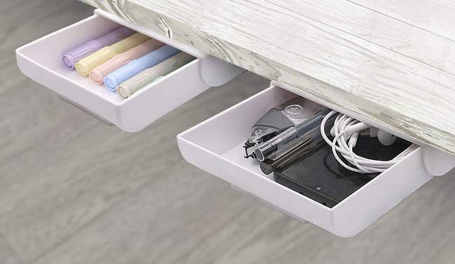 two small white drawers with pens in them installed in the underside of a desk 