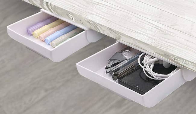 two small white drawers with pens in them installed in the underside of a desk