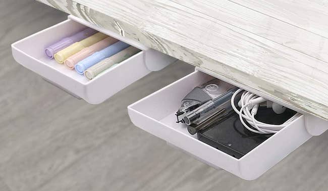 two small white drawers with pens in them installed in the underside of a desk 