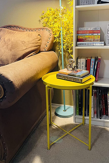 a metal yellow end table with a tray like top in a living room