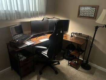 Home bureau   setup with a country   desk, dual monitors, laptop, and ergonomic chair. A level  lamp and tiny  support  are nearby