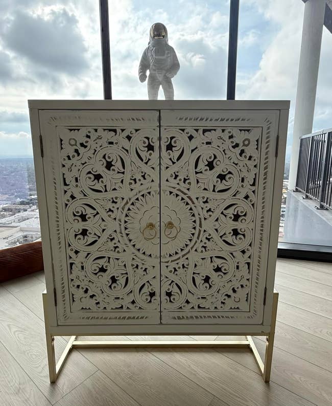 Intricately carved achromatic furniture with golden accents successful a agleam room; astronaut figurine connected top