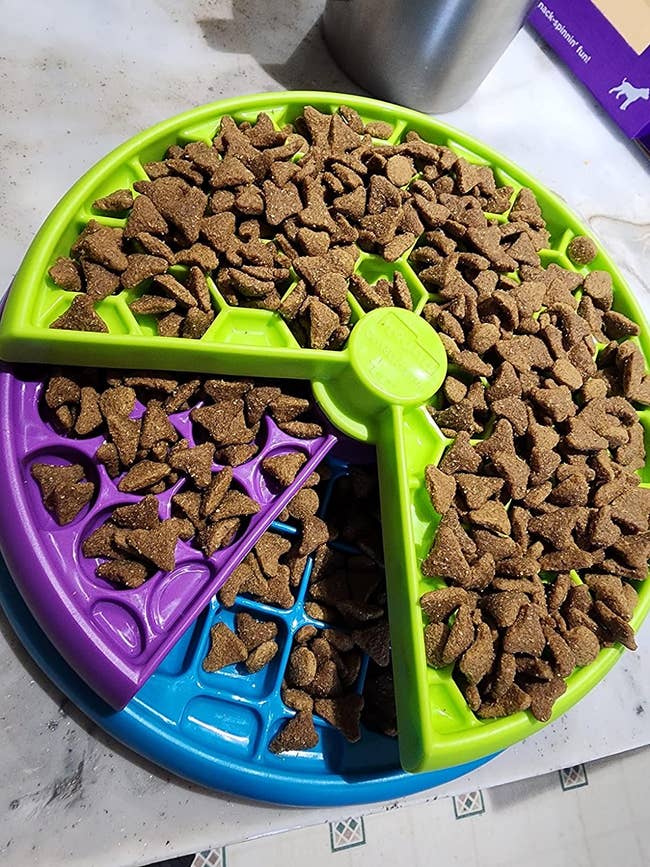 a multi-layer slow feeder puzzle toy with kibble on it