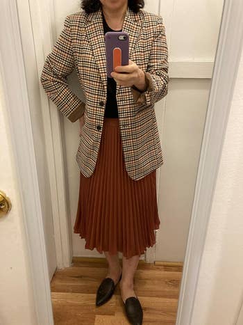 Person in a plaid blazer, pleated skirt, and loafers