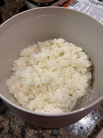 Cooked white rice in a grey bowl on a kitchen counter