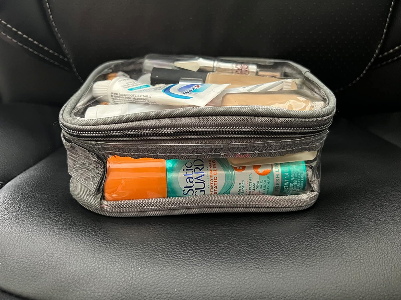 Clear question   toiletry container  filled with a assortment  of travel-sized idiosyncratic   attraction   items, including toothpaste, foundation, and skincare products