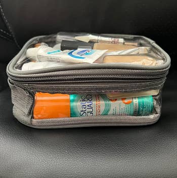 Clear question toiletry container filled with a assortment of travel-sized idiosyncratic attraction items, including toothpaste, foundation, and skincare products