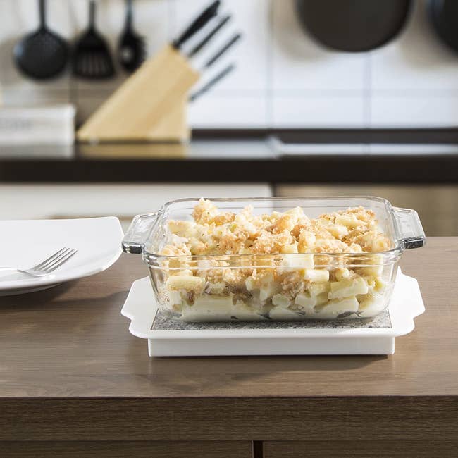 Mac and cheese in a dish on a white square shaped warming plate 