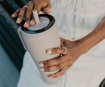 model holding taupe colored tumbler